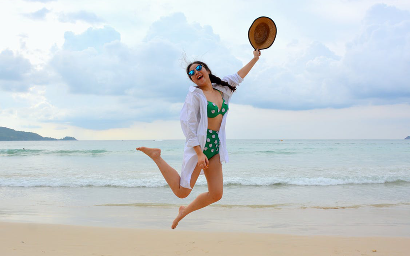 carefree woman jumping for joy at the beach.