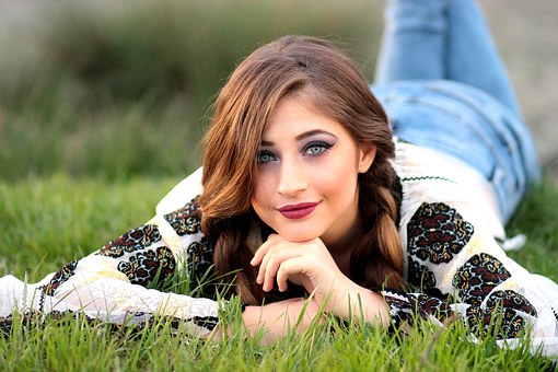 young woman laying down on grass with good skin.